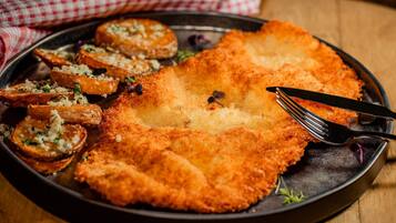 A plate with breaded cutlet, potato slices, and a fork.