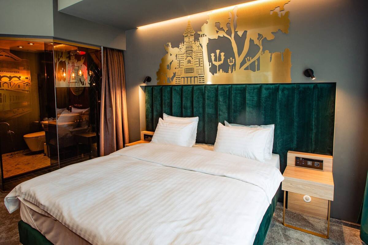A hotel room with a large bed, a nightstand, a mirror, and a wall with a decorative map.
