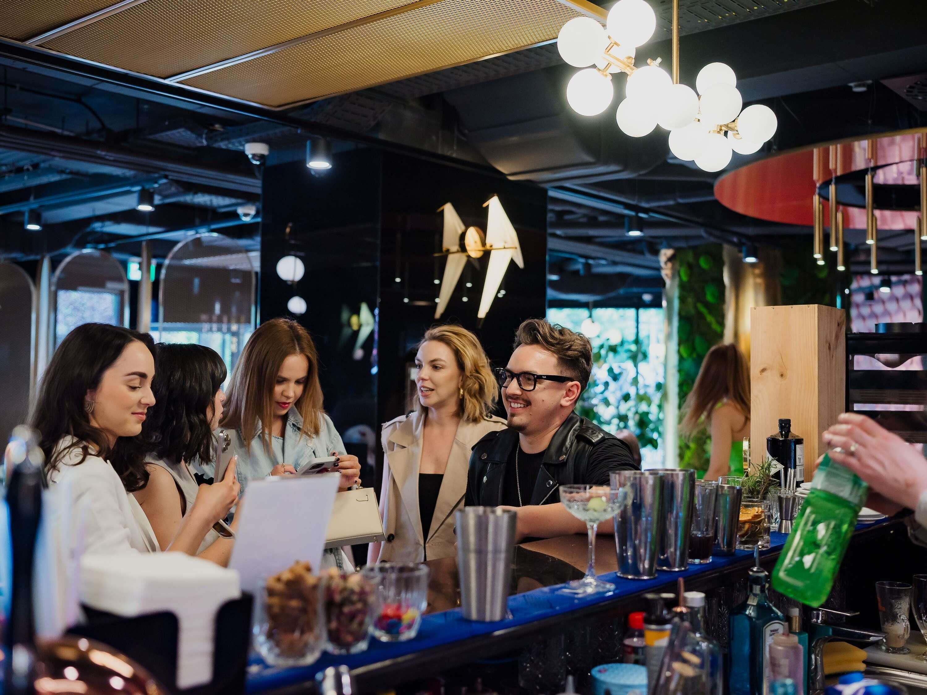 Una zona de bar con mostrador, vasos y botellas.