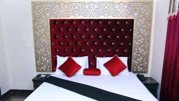 A hotel room with a large bed, a decorative headboard, and a nightstand with a phone. - EXECUTIVE PALACE HOTEL LAHORE (Lahore)