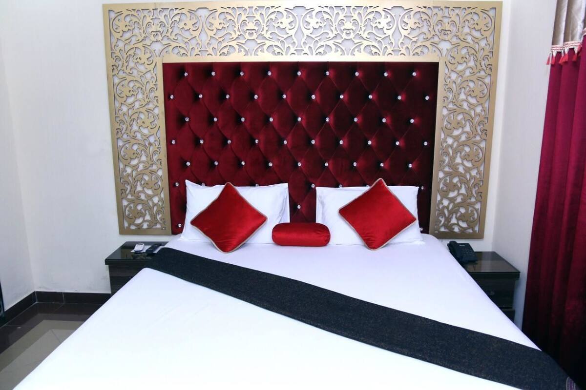 Una habitación de hotel con una cama grande, un cabecero decorativo y una mesita de noche con un teléfono.