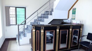 A reception area with a black and gold counter, a glass door, a staircase, and a chair. - EXECUTIVE PALACE HOTEL LAHORE (Lahore)