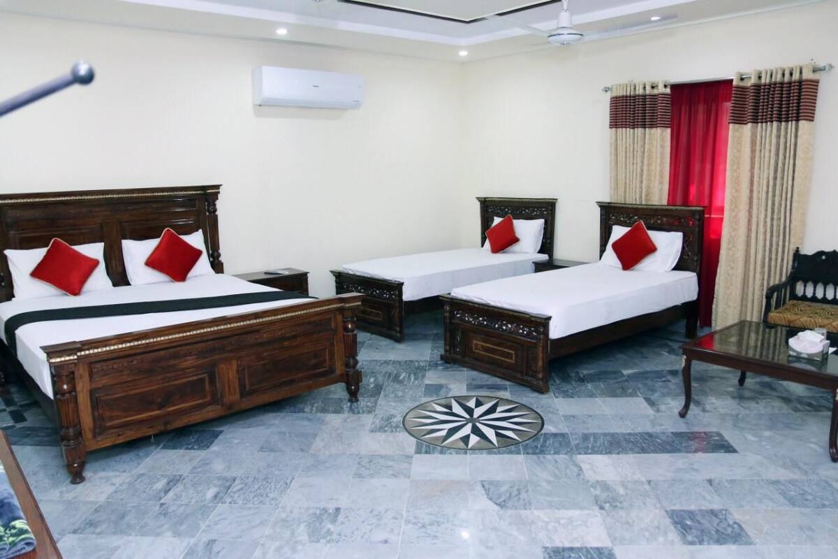 Una habitación de hotel con dos camas de madera, una mesita y una silla.