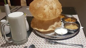 A table with a large bread roll, a glass of milk, and several small bowls of condiments. - EXECUTIVE PALACE HOTEL LAHORE (Lahore)