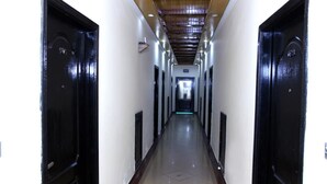 A long, narrow hallway with black doors on either side, leading to a bright room at the end. - EXECUTIVE PALACE HOTEL LAHORE (Lahore)