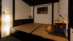Una habitación con tatami, una mesa baja, una lámpara y un cuadro en la pared.