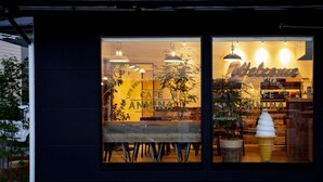 Una cafetería con techo de tejas, amplias ventanas y plantas de interior.