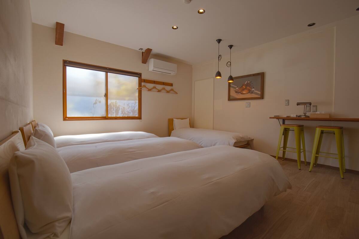 A room with two beds, a small desk, and a chair.