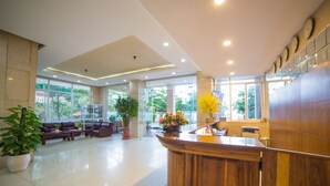 A spacious lobby with a reception desk, seating area, and large windows offering a view of the outdoors. - My Khe 2 Da Nang Seafront Hotel (Da Nang)