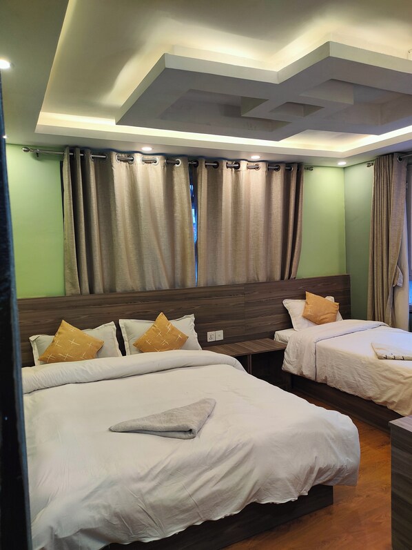 A hotel room with two beds, a wooden headboard, and a large window with curtains.