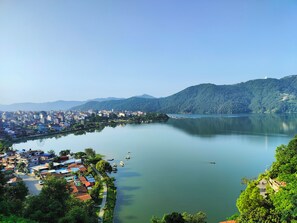 A panoramic view of a lakeside town with buildings along the shore and hills in the background.