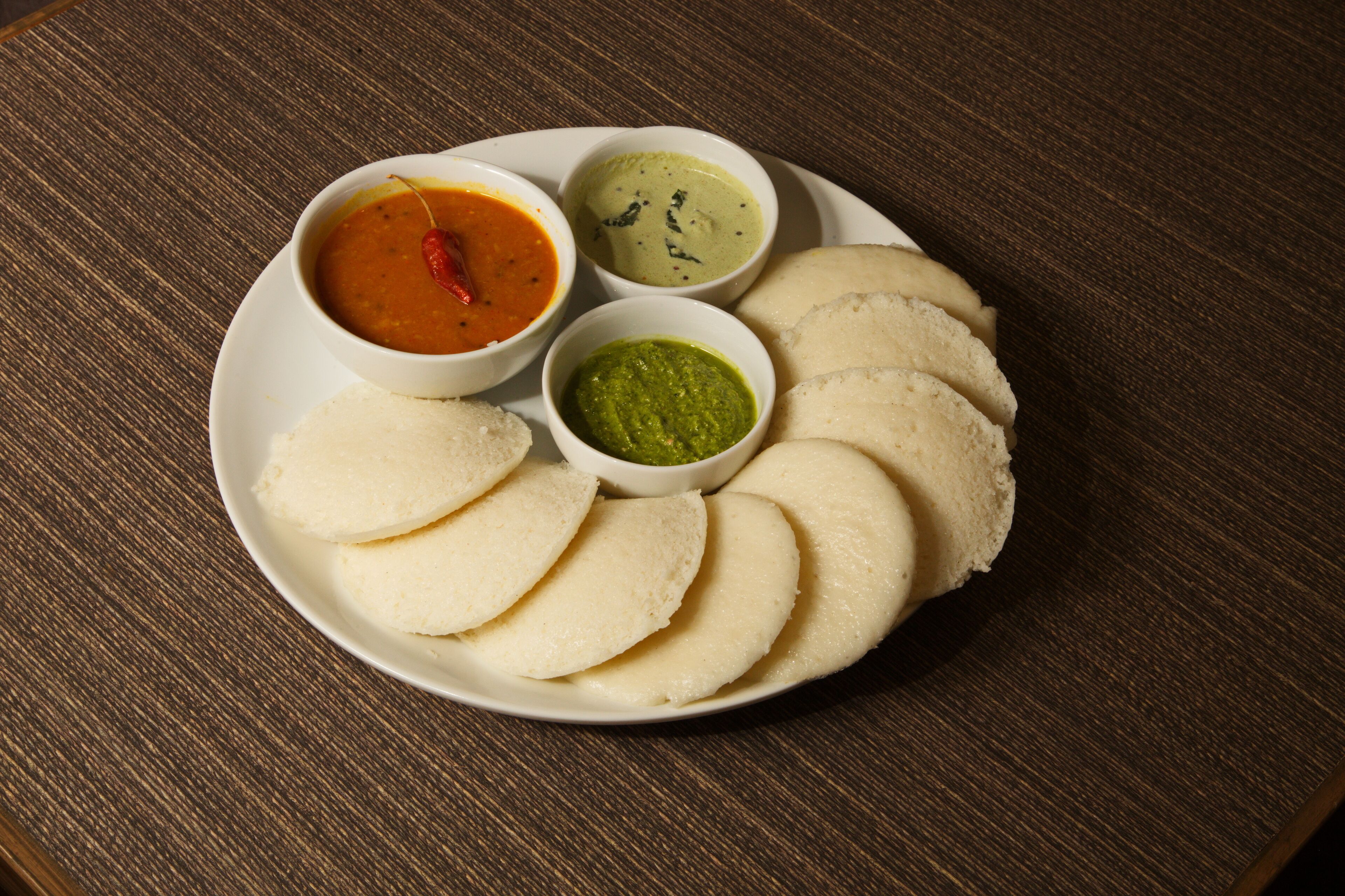 Une assiette de «idlis» accompagnée de trois sauces.