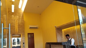 Un espace d’accueil avec un comptoir en marbre, une porte en bois portant l’inscription « Interdiction de fumer » et un appareil de climatisation fixé au mur.