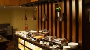 Un buffet proposant une variété de plats, avec un mur en panneaux de bois et des luminaires suspendus.