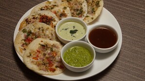 Une assiette de nourriture accompagnée de trois sortes de chutney et d’une sauce foncée.