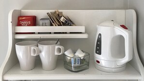A white shelf with a white kettle, two white mugs, a glass container with milk, and a pack of Barry's Tea. - Westwinds (Galway)