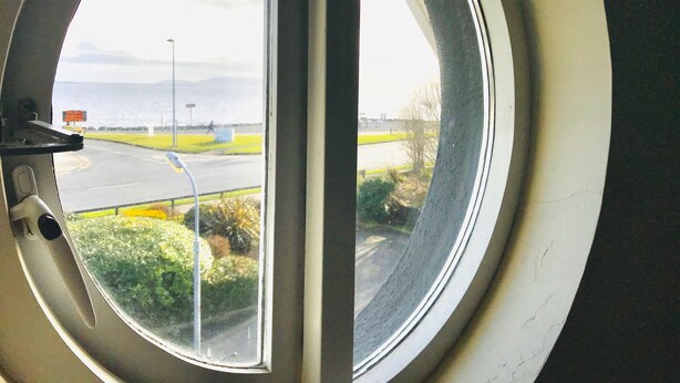 A window with a view of a road and greenery. - Westwinds (Galway)