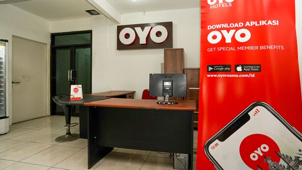 Un espace d’accueil comprenant un comptoir, des chaises, un réfrigérateur et une grande enseigne OYO Hotels.