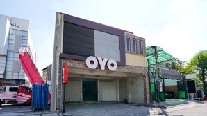 Un bâtiment sur lequel est apposée une grande enseigne indiquant « OYO », et un camion rouge garé devant.