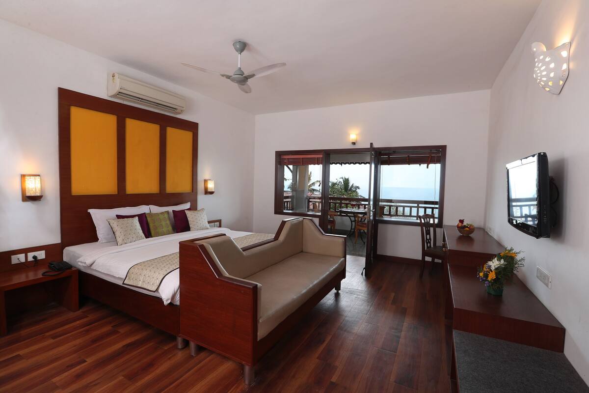 Ein Hotelzimmer mit Bett, Sofa, Fernseher und einem Balkon mit Blick.
