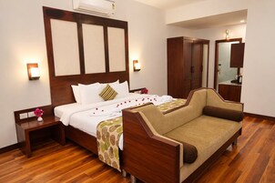 Habitación de hotel con cama de madera, sofá, armario, mesita de noche y espejo.