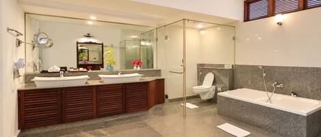 Un baño moderno con un espejo grande, dos lavamanos, inodoro y bañera.