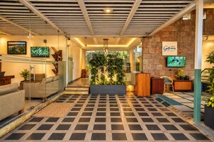 Una moderna zona de recepción con suelo a cuadros, mostrador de recepción, área de estar y televisor montado en la pared.
