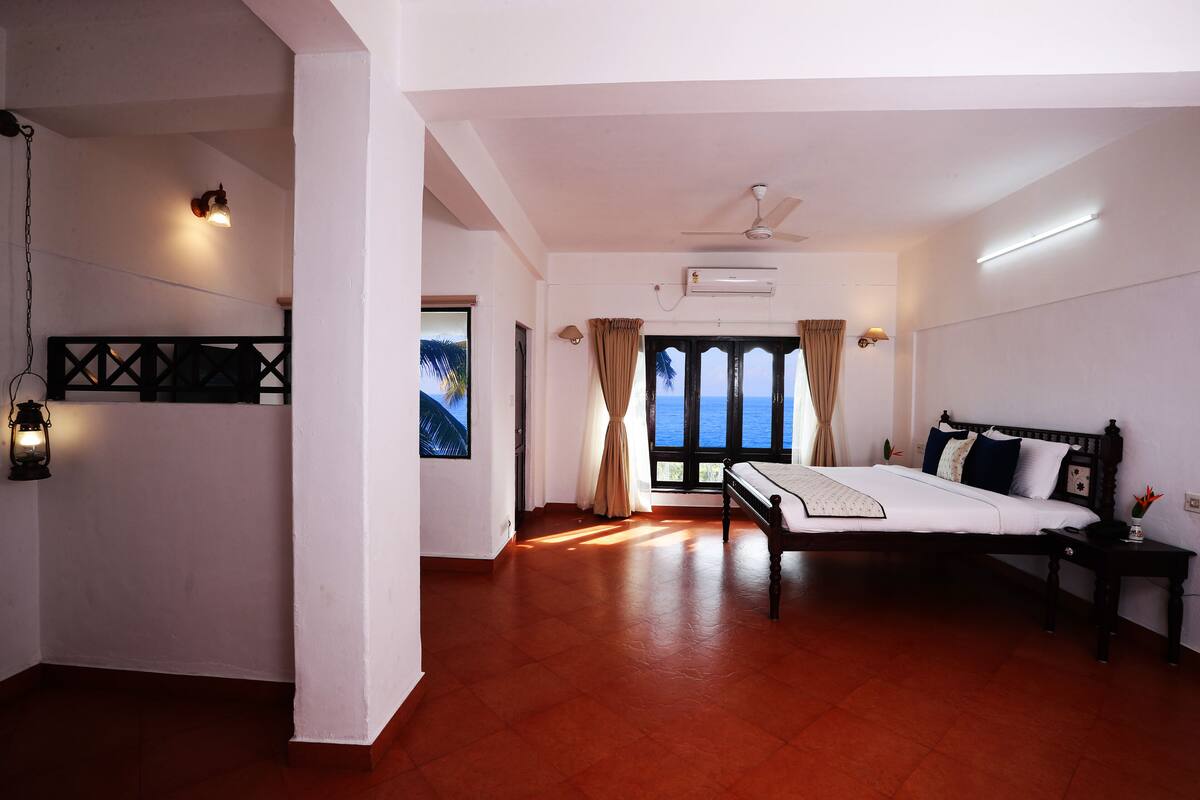 Ein Schlafzimmer mit Bett, Deckenventilator, Klimaanlage und Meerblick durch das Fenster.