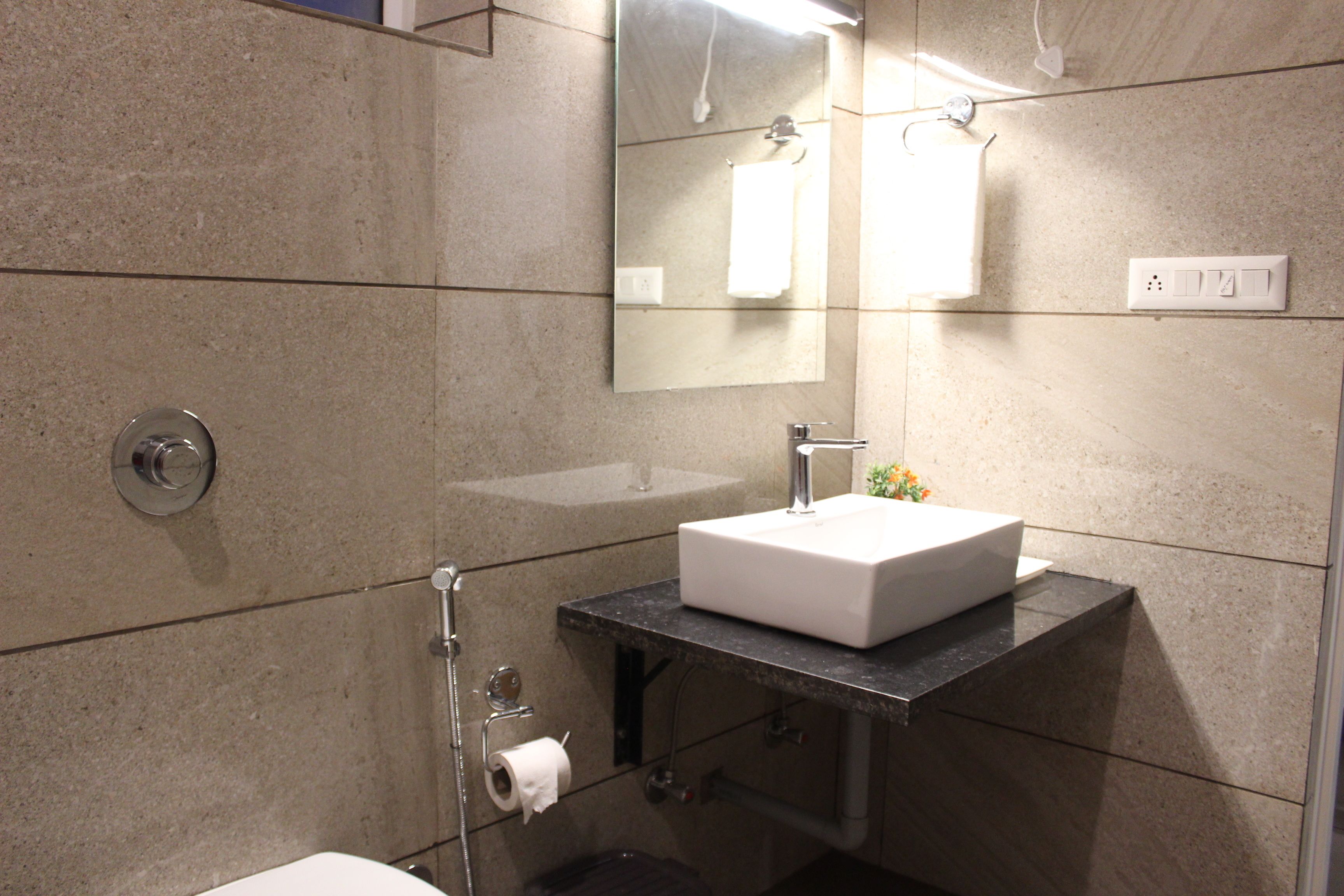A modern bathroom with a white sink, a mirror, and a towel hanging on the wall.