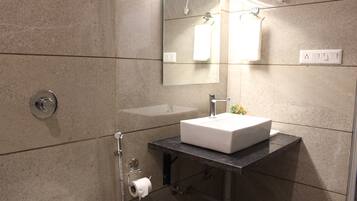 A modern bathroom with a white sink, a mirror, and a towel hanging on the wall.
