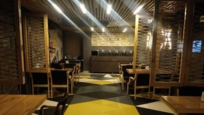A restaurant interior with a geometric patterned floor, wooden tables and chairs, and a wall with repeated 'ROCK' text. - Hotel Sai (Bawal)
