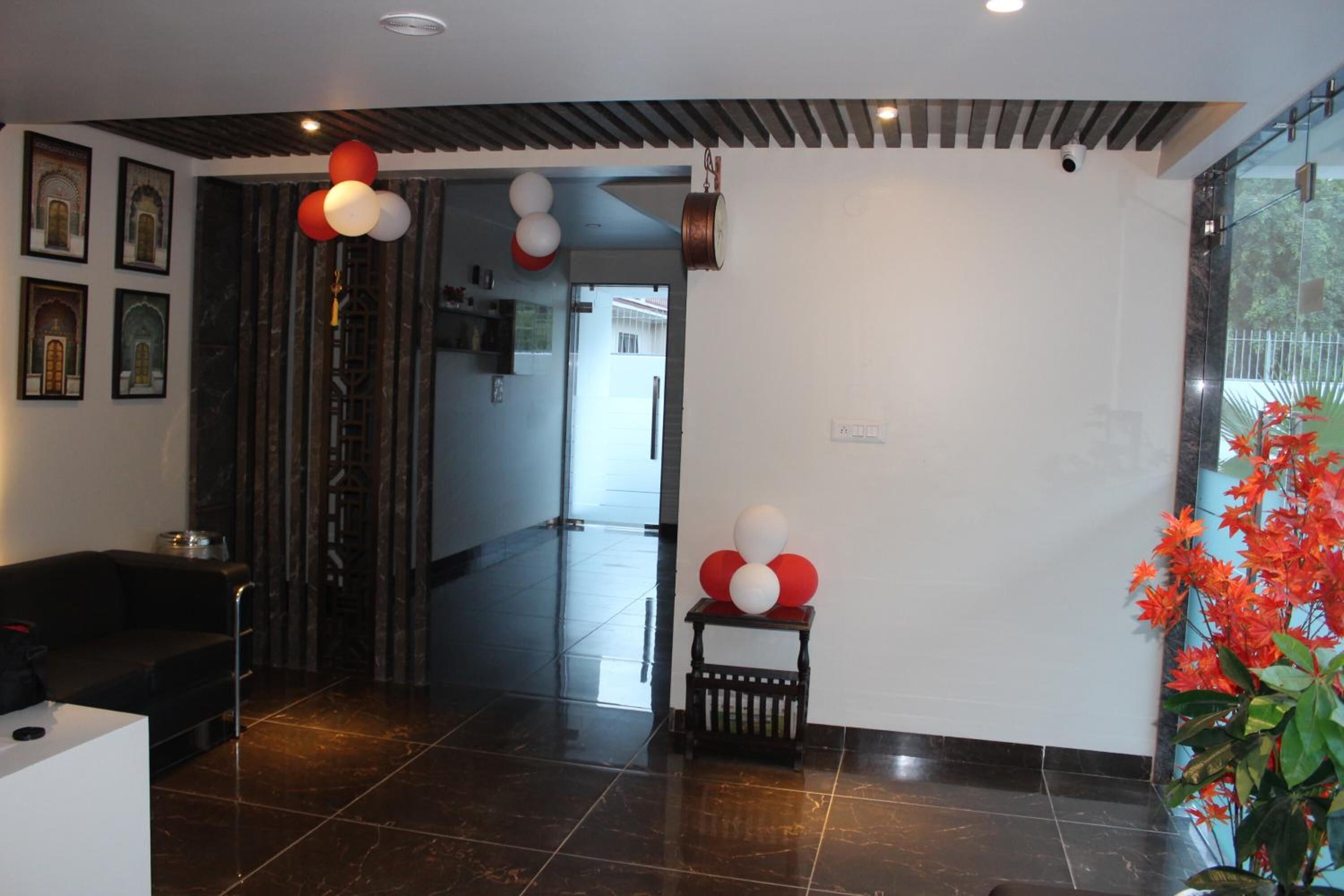 A modern lobby with a reception desk, a staircase, and a potted plant.