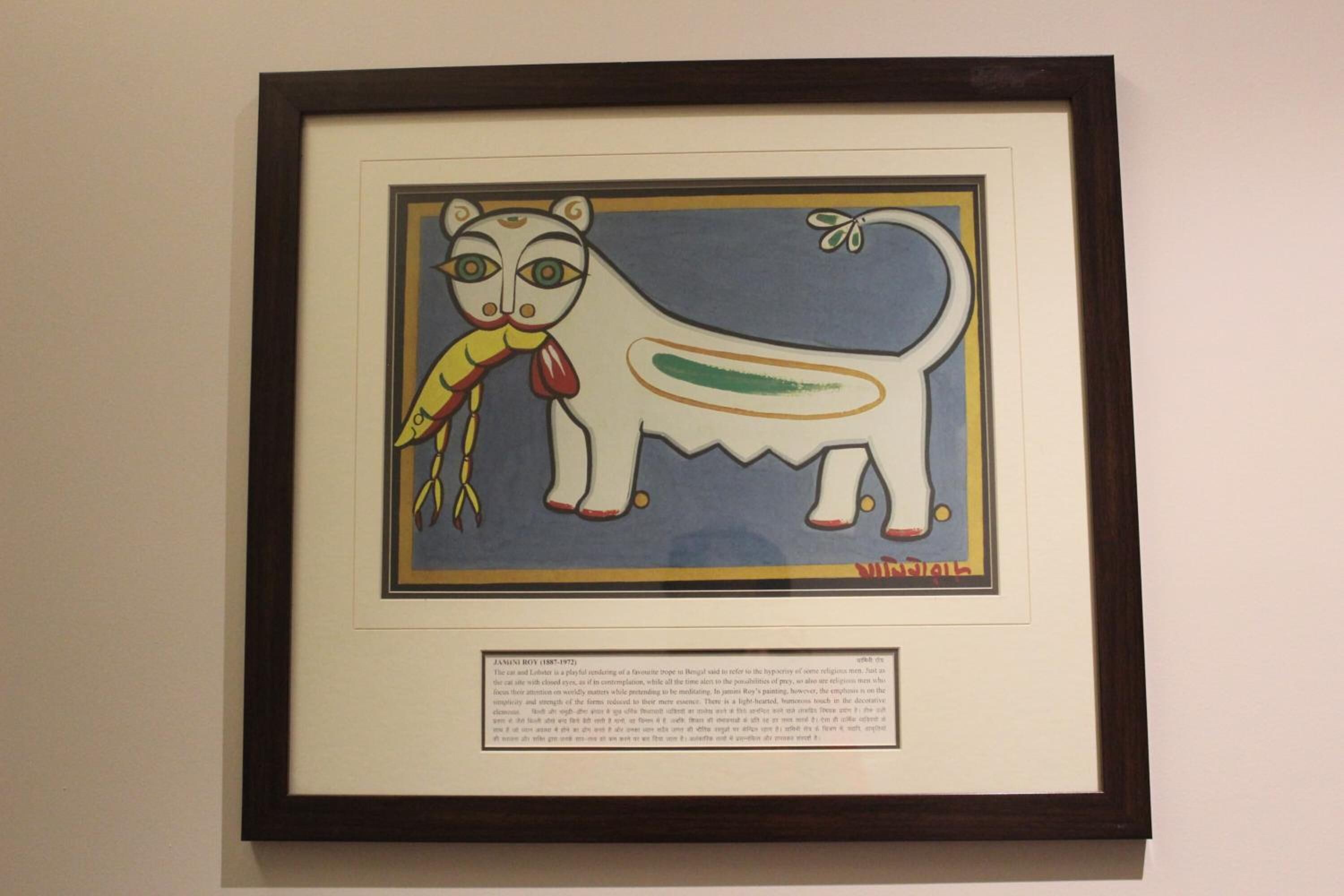 Una obra de arte en marco con un gato y un pájaro, y un texto descriptivo debajo.