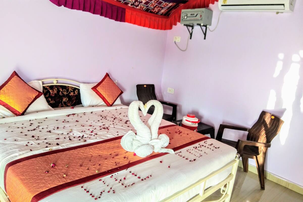 A hotel room with a bed, a chair, an air conditioner, and a wall-mounted heater.