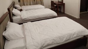 A hotel room with two single beds, a wooden headboard, a small wooden table, and a chair. - Alwalajy towers (Jericho)