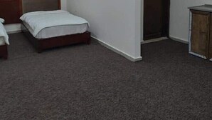 A room with two single beds, a wooden wardrobe, and a carpeted floor. - Alwalajy towers (Jericho)