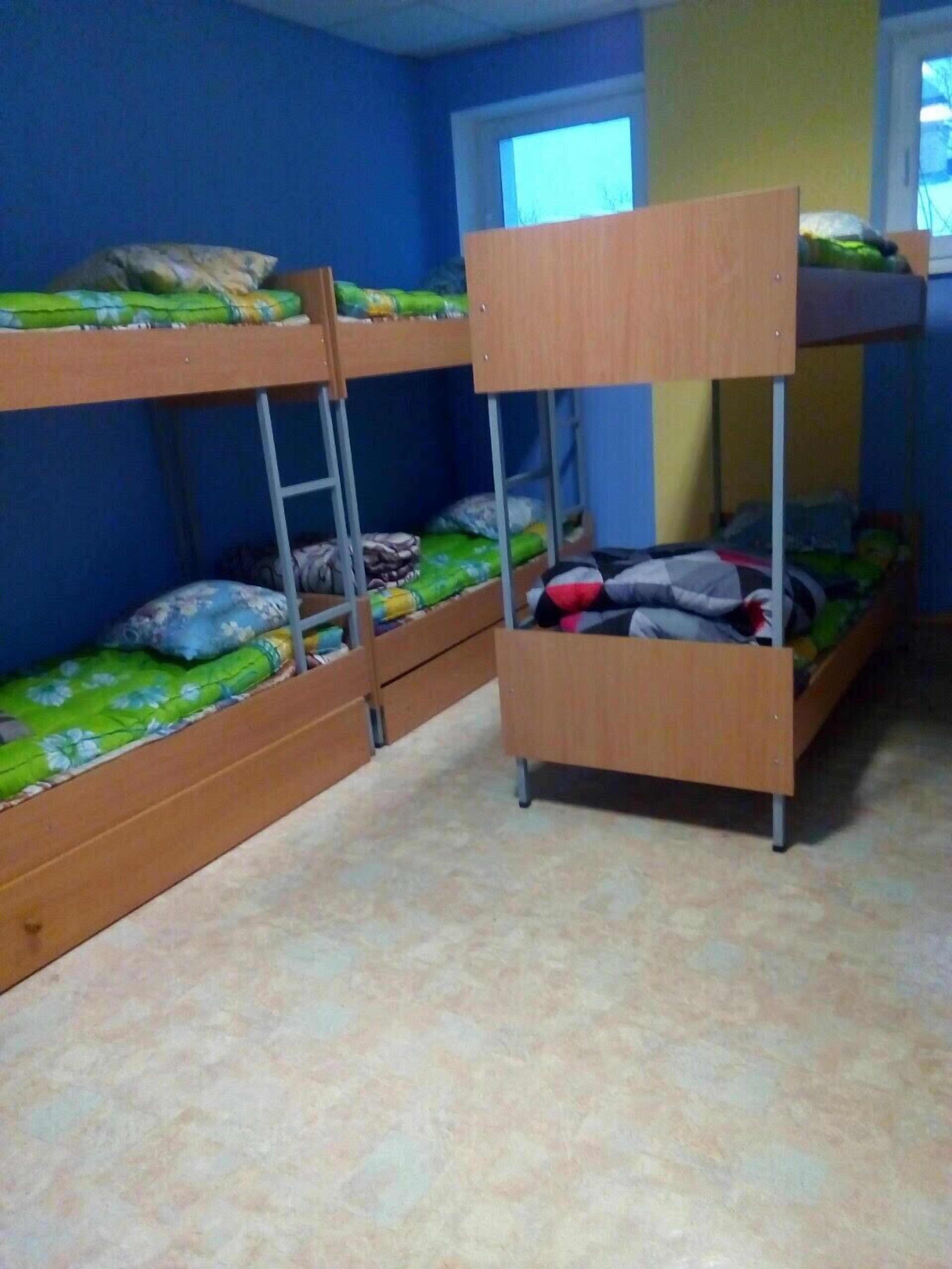 A bunk bed room with blue walls and a window.