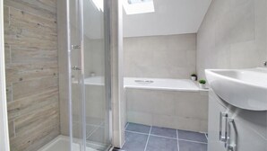 Uma casa de banho moderna com chuveiro, banheira e lavatório.