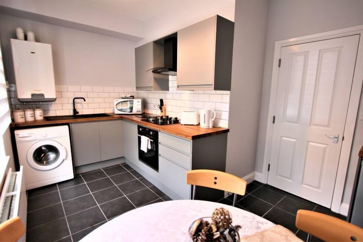 A compact kitchen with a washing machine, microwave, and stove.