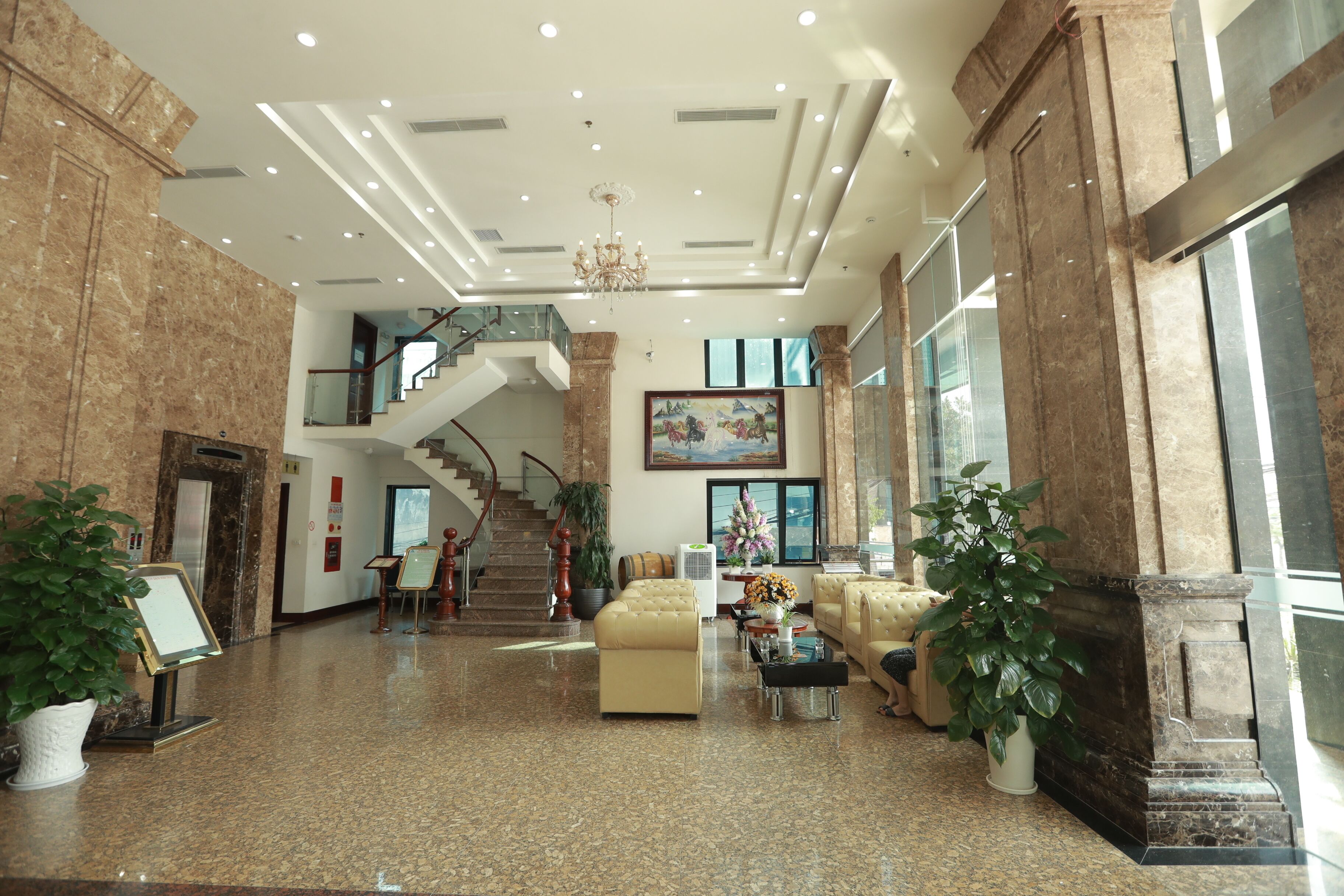 A spacious lobby with a marble floor, a staircase, and a large painting on the wall.