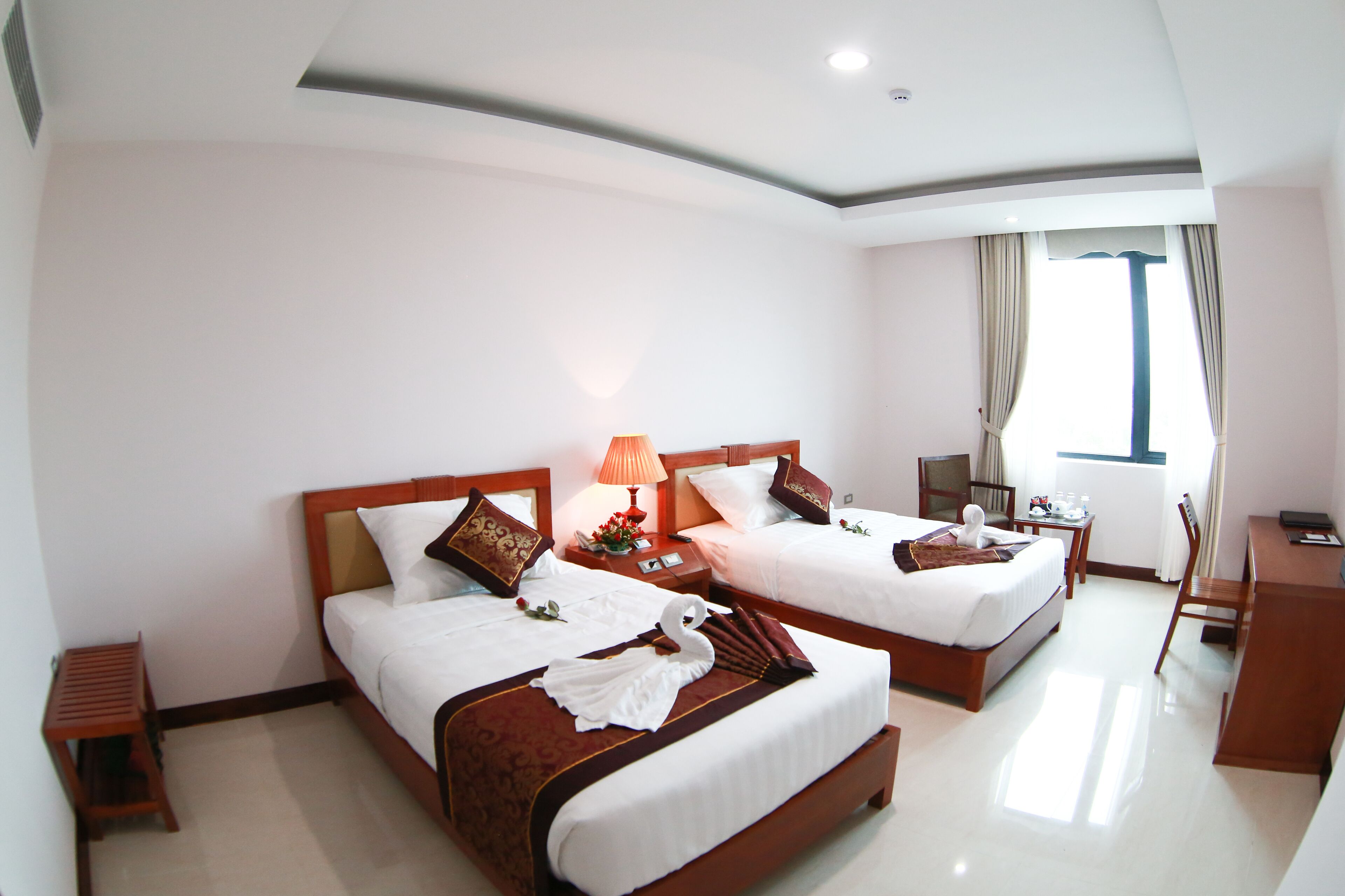 A hotel room with two beds, a desk, and a chair.