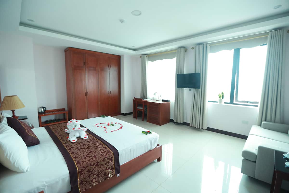 Una habitación de hotel con una cama, un escritorio, un armario y un sofá.