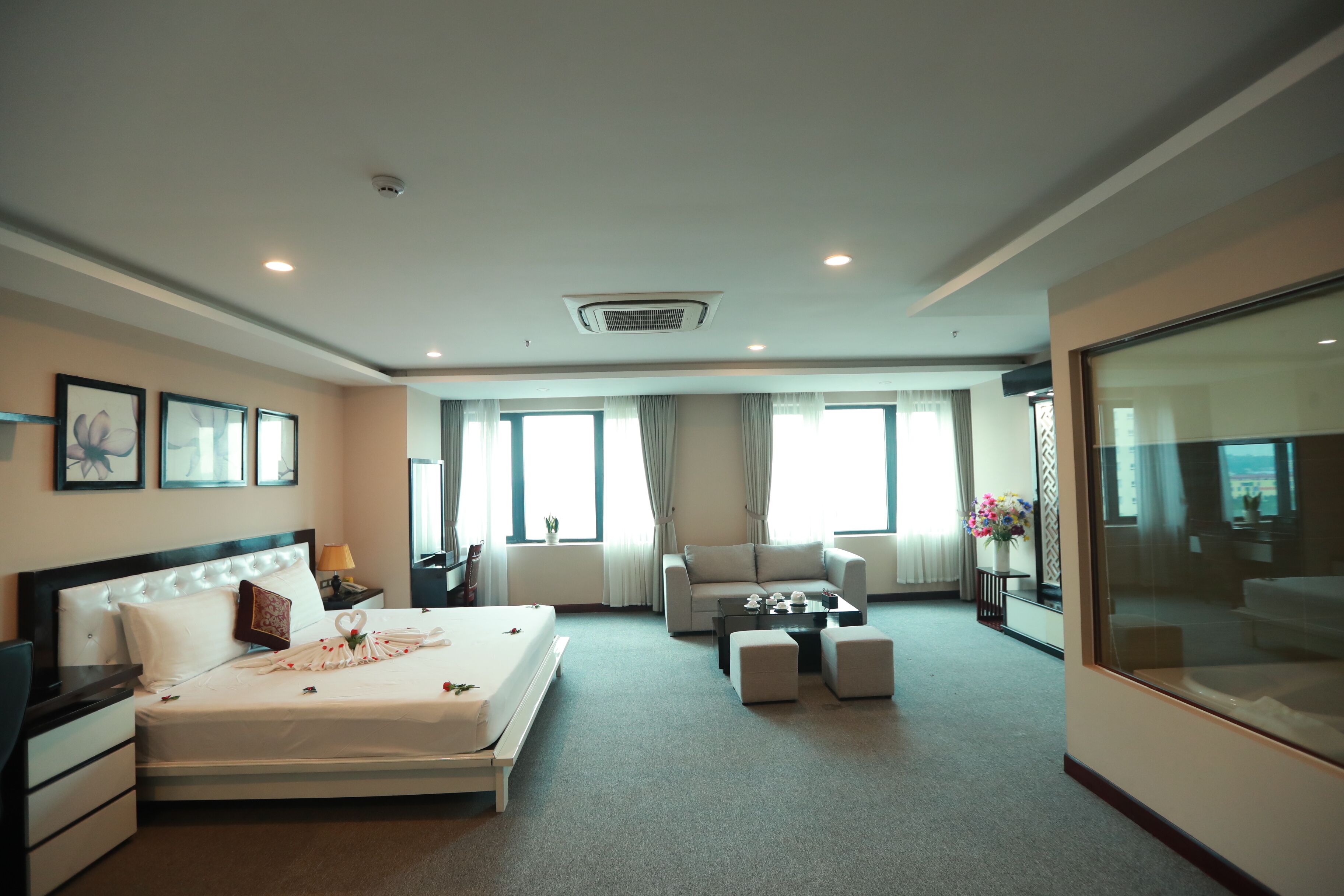 Habitación de hotel con una cama grande, un sofá, una mesa de centro y un televisor.
