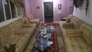 A living room with two sofas, a coffee table, a fan, and a chandelier. - Youth guest house (Wadi Musa)