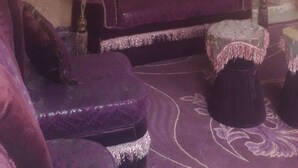 A living room with a purple sofa set, a small round table, and a mirror on the wall. - Youth guest house (Wadi Musa)
