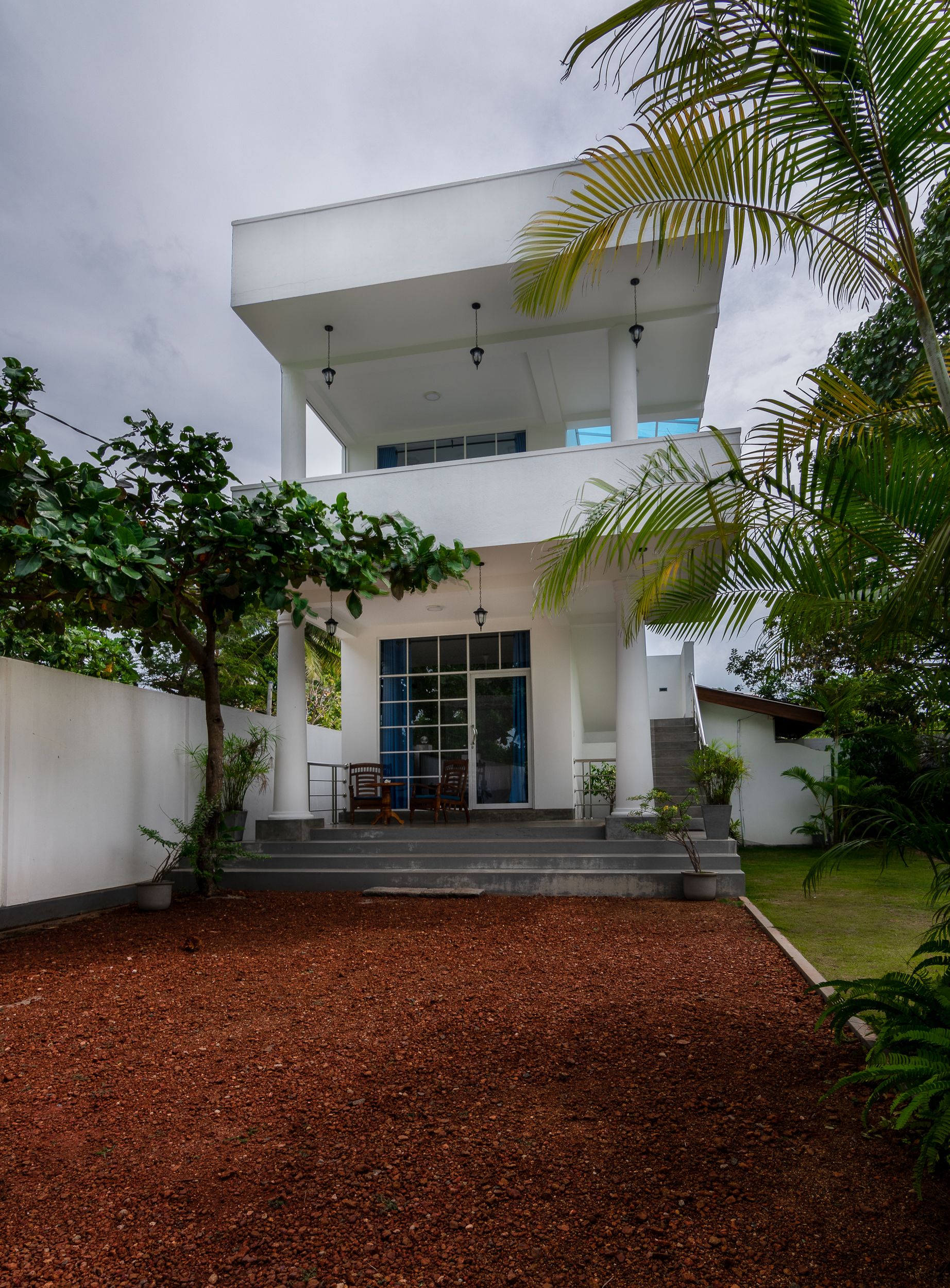 A modern two-story building with a flat roof, large windows, and a covered entrance area with steps leading up to it.