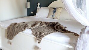 A bed with a white headboard, a knitted blanket, and a blue seahorse pillow. - ARYA Boutique Resort (Kiwengwa)