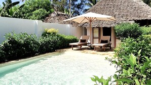 A clear pool with lounge chairs and a thatched-roof structure, surrounded by lush greenery. - ARYA Boutique Resort (Kiwengwa)
