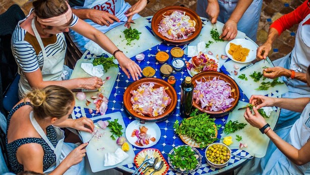 A group of people preparing food around a table with various ingredients and utensils. - Riad Dar Lfonoun (Marrakech)