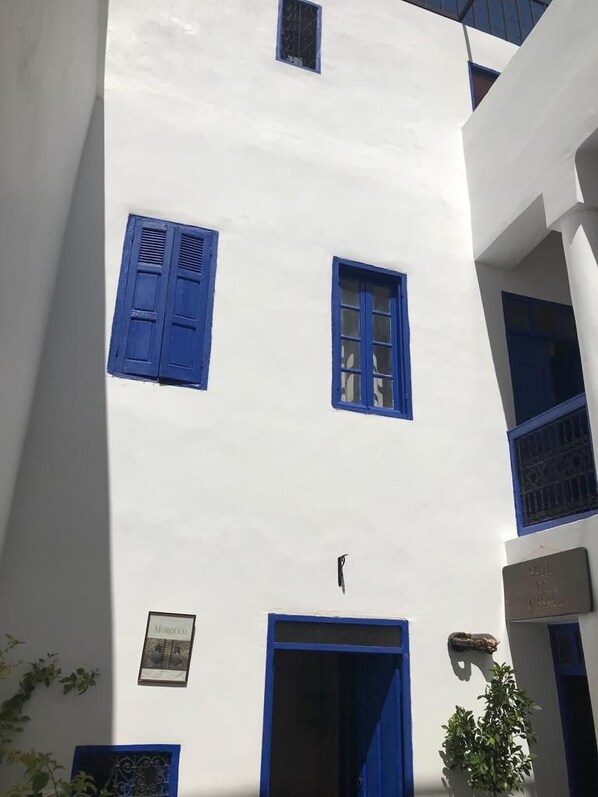 A white building with blue shutters and a door, featuring a framed picture on the wall. - Riad Dar Lfonoun (Marrakech)